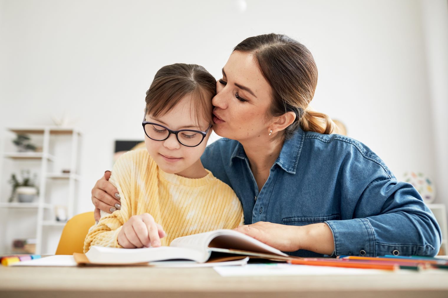 Portrait of mother kissing daughter with Down syndrome